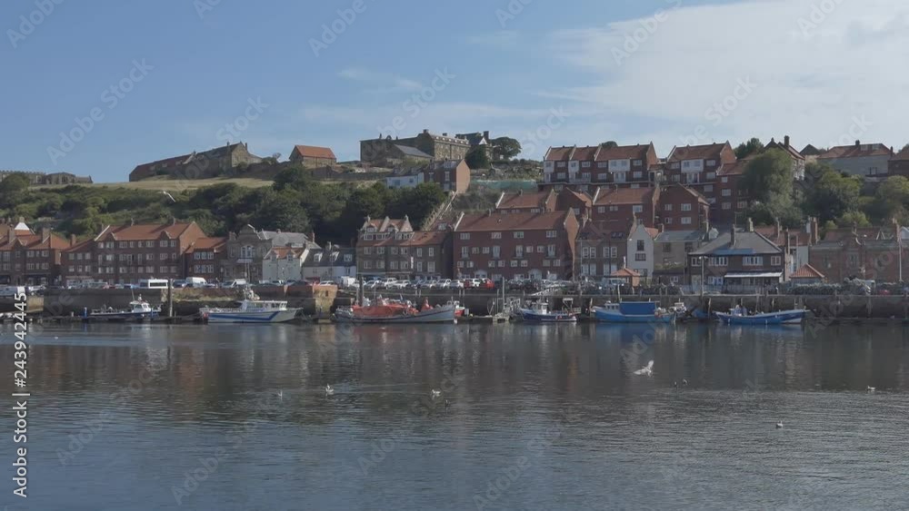 Panning shot of a town riverside with boats on a wharf. Panning shot of a town riverside with boats on a wharf.