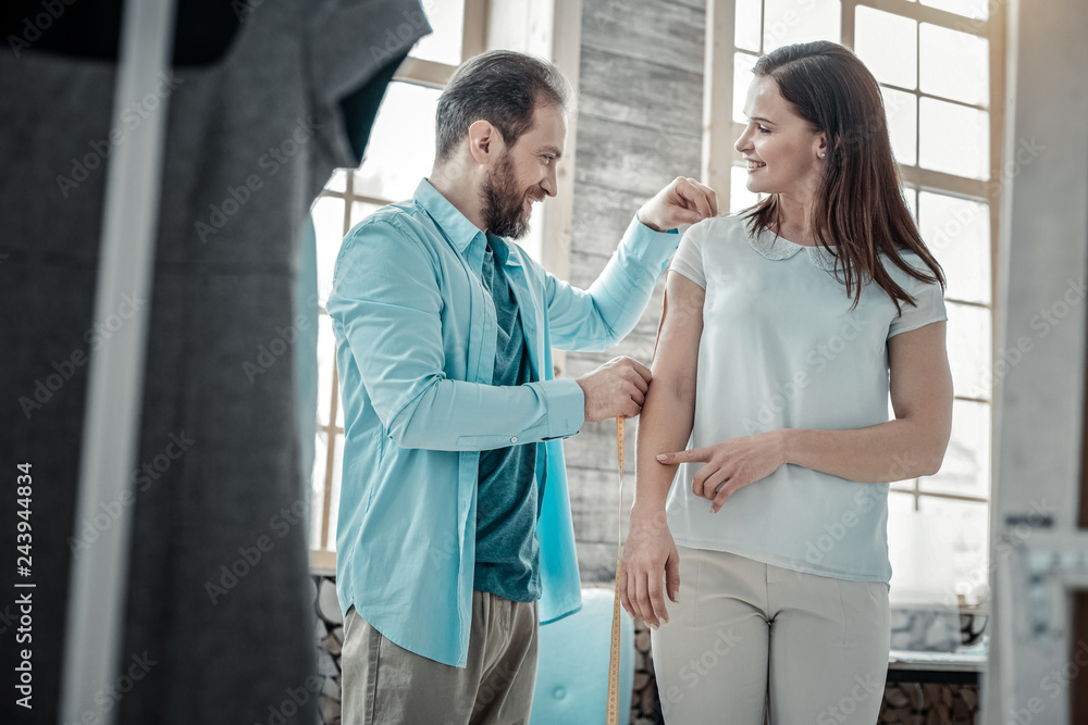 Fototapeta premium Bearded male designer making measurements of his client