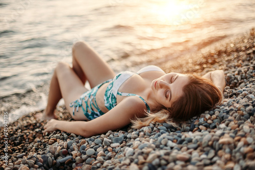 Beautiful young woman posing in bikini on the beach. Female fashion model posing in swimsuit on sea shore