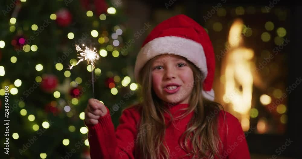 The slow motion of cute cheerful little girl wearing santa hat singing a Christmas Song with sparklers in her hands. Shot with RED camera in 8K. Concept of Christmas time, winter holidays, family fun. The slow motion of cute cheerful little girl wearing santa hat singing a Christmas Song with sparklers in her hands. Shot with RED camera in 8K. Concept of Christmas time, winter holidays, family fun.