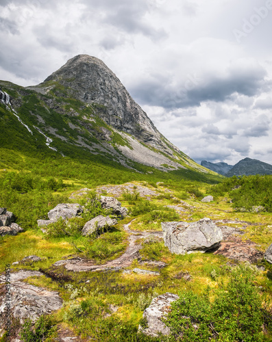Beautiful mountain scenery near Trollstigen road from Andalsnes to Stranda in Norway, Scandinavia. Summer landscape with green grass and large picturesque stones in the foreground.