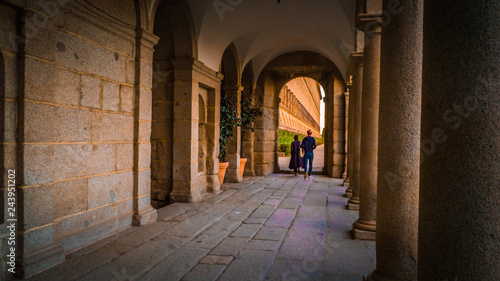 People walk between columns at Frailes garden at the El Escorial monastery and royal site during fall time near Madrid, Spanish capital.