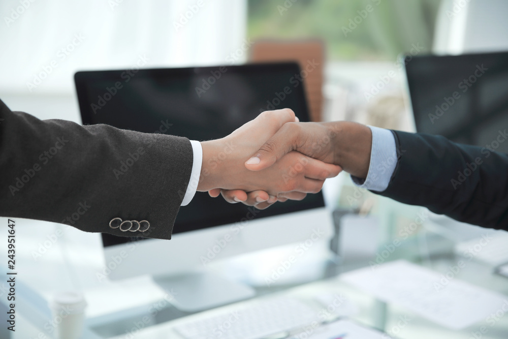 handshake financial partners over a Desk in the office handshake financial partners over a Desk in the office