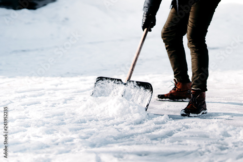 close up of adult cleaning snow from sidewalk and using snow shovel after heavy snowstorm