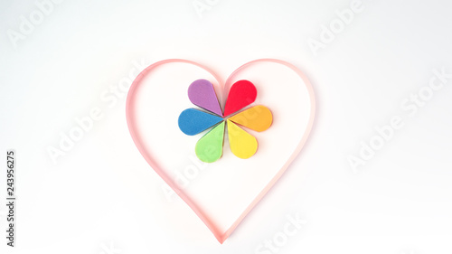 Gay pride, homosexual, Valentine's day and lgbt concept - pink paper heart and colorful make-up cosmetics sponges in rainbow color LGBT flag on white background. Copy space, flat lay, horizontal