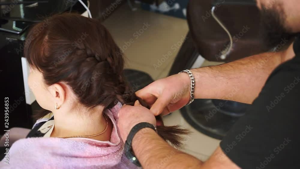 Master man makes pigtails on head of young girl