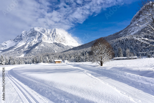Winter mountain landscape with groomed ski trails and blue sky in sunny day. Ehrwald valley, Tirol, Alps, Austria, Zugspitze Massif  in background. © msnobody
