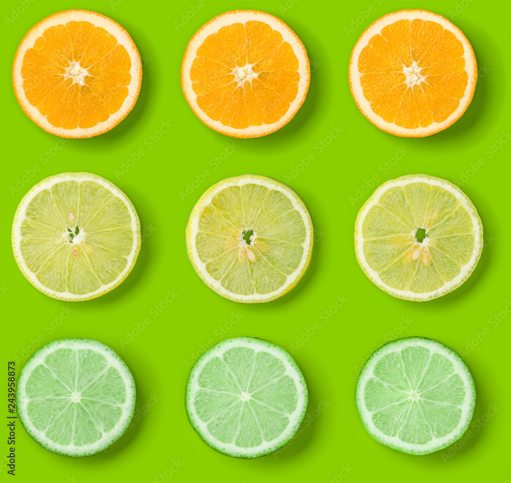 Fototapeta premium Citrus Fruits pattern on green background. Orange, Lime, Lemon slices background. Flat lay, top view.