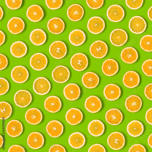 Fruit pattern of orange slices on green  background. Flat lay, top view. Food background.