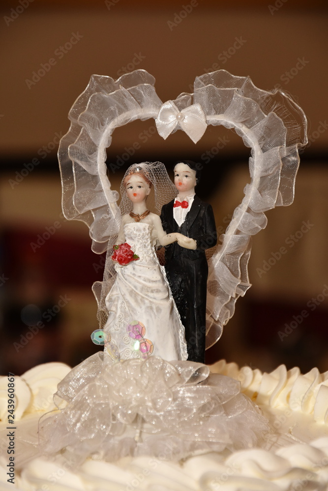 Bride and groom couple doll on wedding cake.