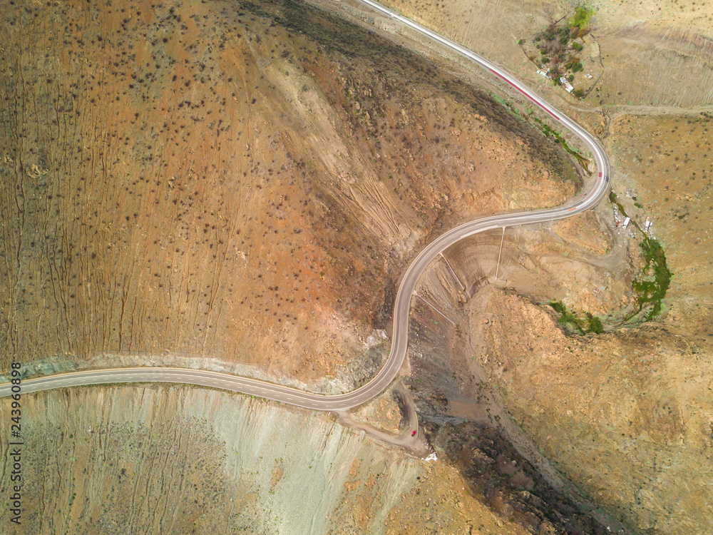 An aerial view from the drone of a road in Atacama Desert, Chile, the road make bends around the arid landscape in order to go down on the cliff to get to the beach, amazing textured pattern
