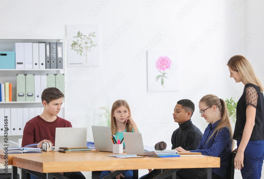 Group of teenagers doing homework with teacher in classroom Group of teenagers doing homework with teacher in classroom