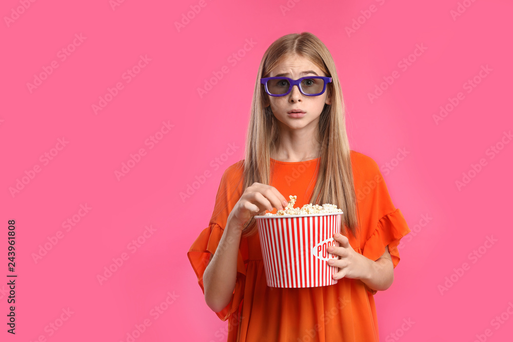 Naklejka premium Emotional teenage girl with 3D glasses and popcorn during cinema show on color background