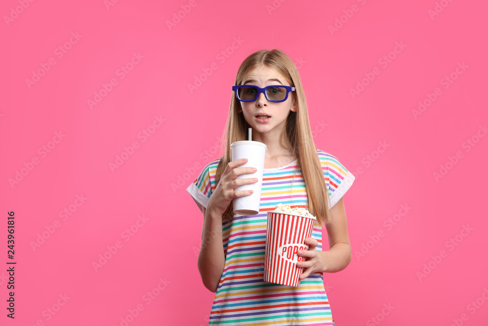 Emotional teenage girl with 3D glasses, popcorn and beverage during cinema show on color background Emotional teenage girl with 3D glasses, popcorn and beverage during cinema show on color background