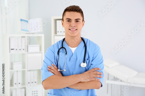Young medical assistant with stethoscope in clinic photo