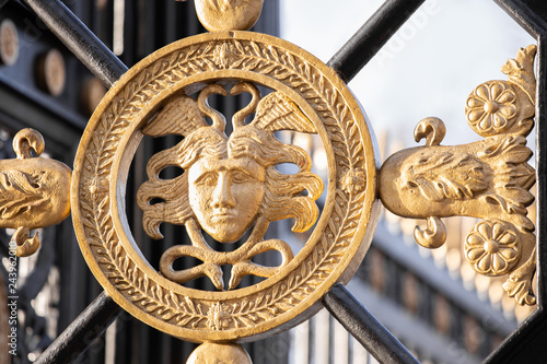 Fotografie Fragment Of Metal Gate With Elements Of Forged Decor And Gold Plated Antique Head