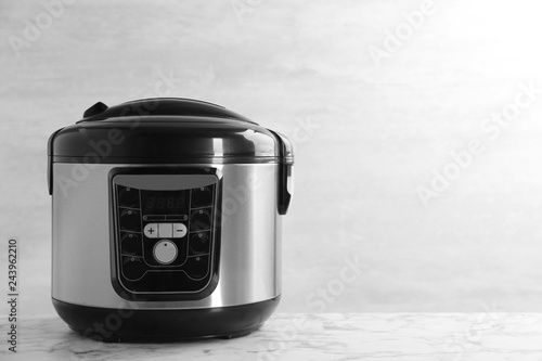 Modern powerful multi cooker on table against light background. Space for text