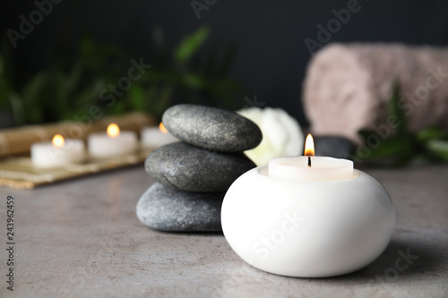 Spa composition with burning candle on table, space for text
