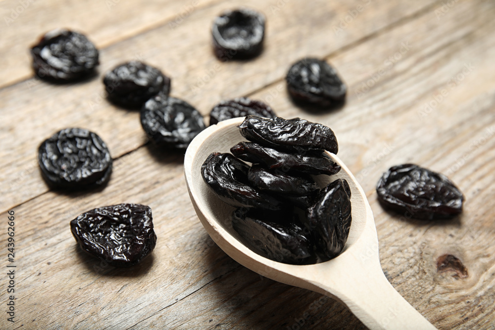 Spoon of dried plums on wooden background, closeup. Healthy fruit Spoon of dried plums on wooden background, closeup. Healthy fruit