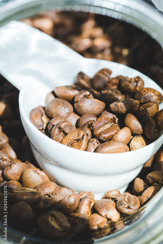 ose up Roasted coffee beans in container, spoonful of bean ose up Roasted coffee beans in container, spoonful of bean