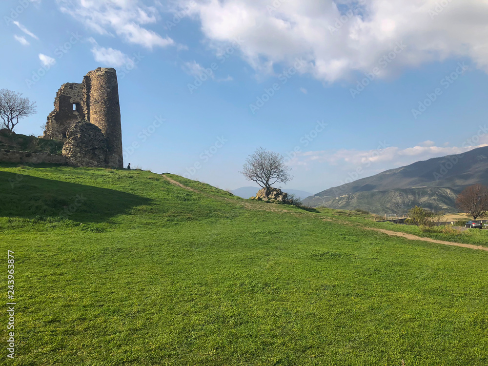 Ruins of an old fortress against the sky, panoramic view. Spring, green fields