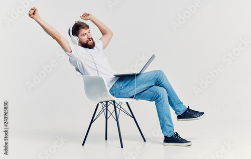 man sitting on a chair with headphones listening to music on his lap laptop