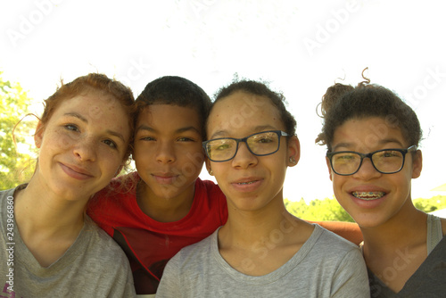 Four siblings of color pose for a family portrait. 