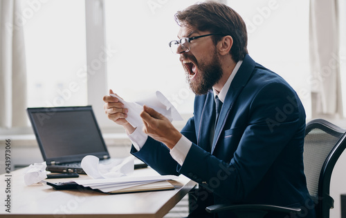 business man shouting sitting at a desk with a laptop office