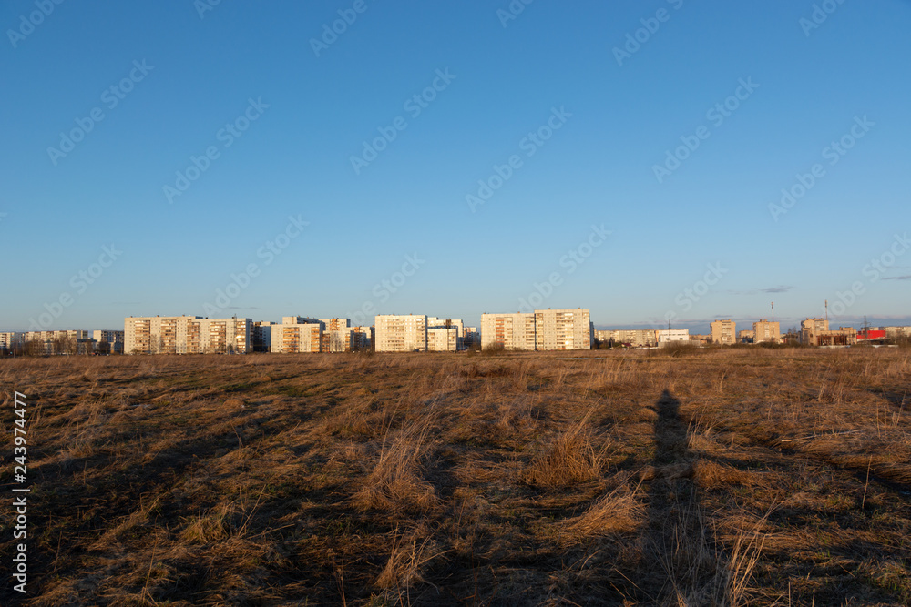 View of multi-storey panel houses from a spring field from afar