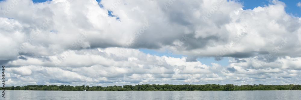 Big white clouds on the blue sky above the river. Big white clouds on the blue sky above the river.