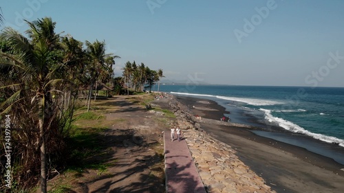 4K aerial drone flying footage of young couple on the wild black sand beach. Bali island.