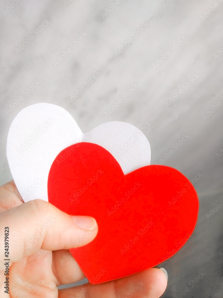 Fototapeta premium Red and white hearts from paper in hand as a symbol of love, care, gift