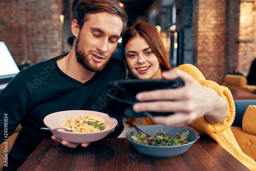young couple taking selfie on a smartphone sitting in a cafe