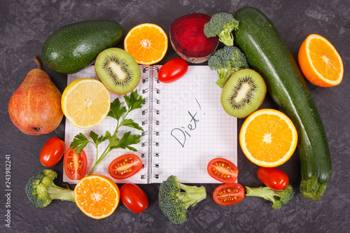 Notepad and fruits with vegetables containing vitamins and minerals  slimming and diet concept