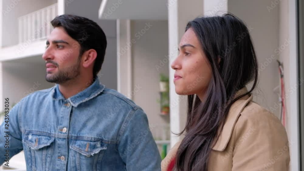 Couple at terrace of a high rise apartment building complex in an urban city they bought new on handheld stabilized shot Couple at terrace of a high rise apartment building complex in an urban city they bought new on handheld stabilized shot