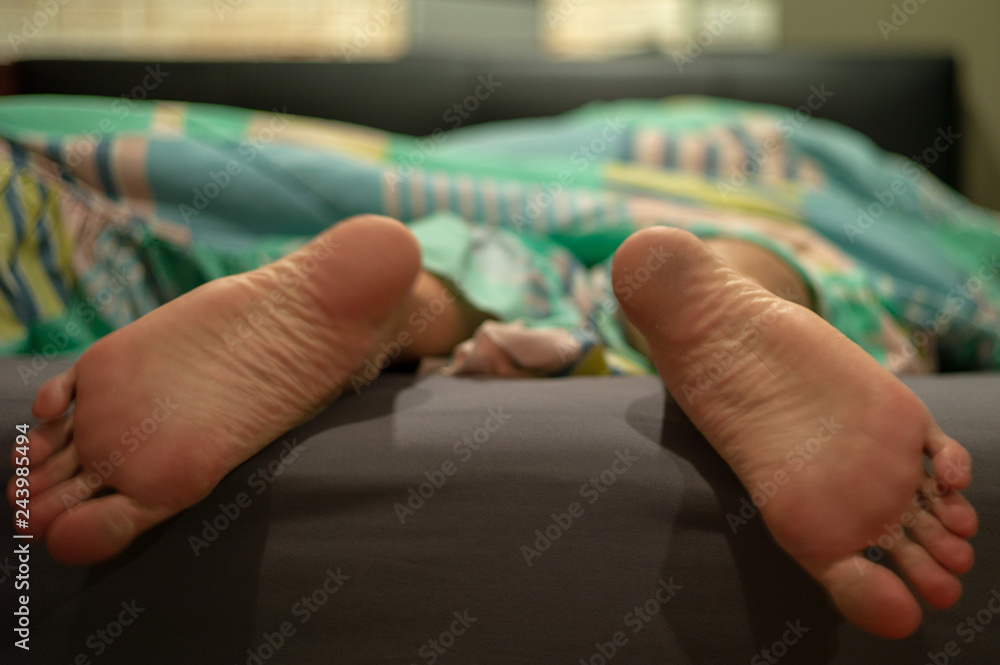 Closeup dirty feet of man sleeping on the bed in bedroom Closeup dirty feet of man sleeping on the bed in bedroom