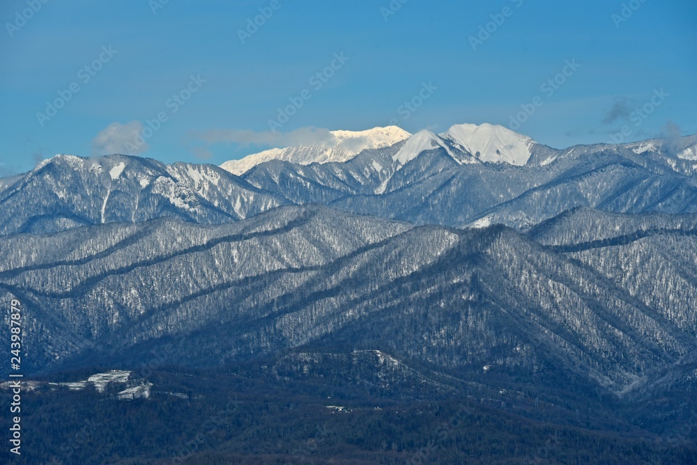 Panorama of snowy mountains. Winter forest and rocky peaks in the snow. Sunny winter day. Panorama of snowy mountains. Winter forest and rocky peaks in the snow. Sunny winter day.