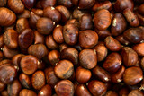 Background with brown fresh chestnuts with peel in autumn