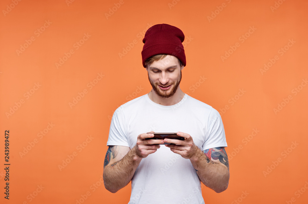 man in a cap wearing a white t-shirt looks into the smartphone phone man in a cap wearing a white t-shirt looks into the smartphone phone