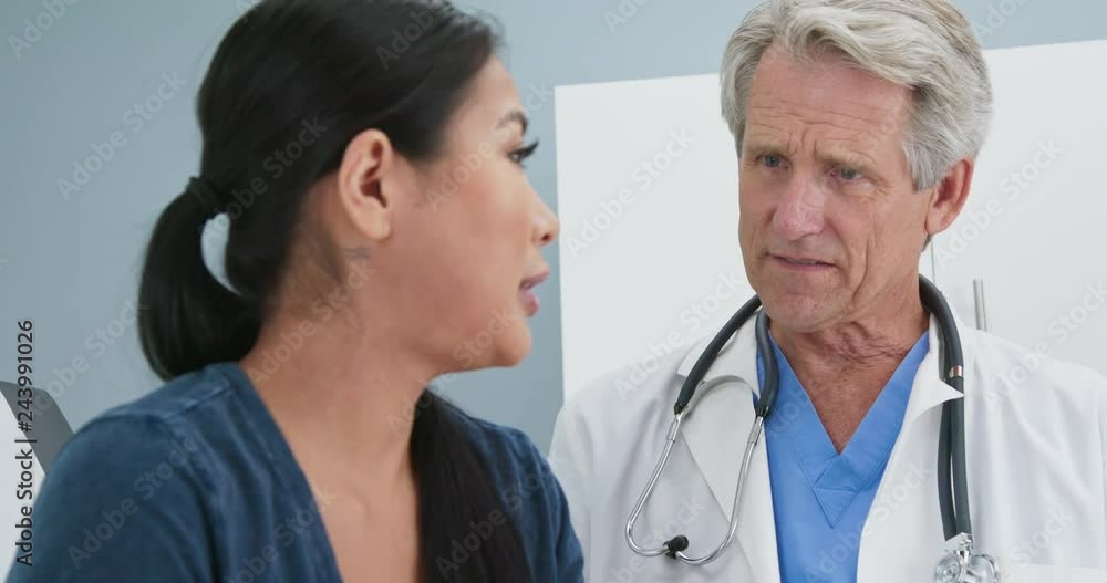 Close up of Senior doctor asking female patient about neck pain in exam room Close up of Senior doctor asking female patient about neck pain in exam room