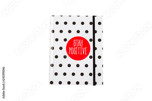 Black and white polka dot note book with red circla and stay positive inscription on the cover. photo