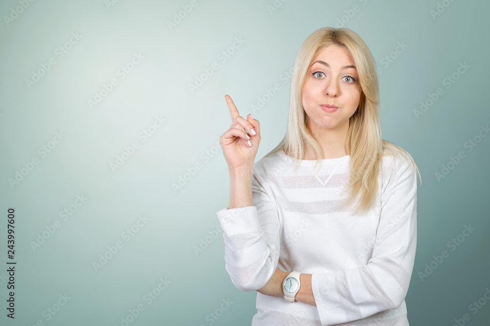 Young woman looking up and pointing at blank wall Young woman looking up and pointing at blank wall