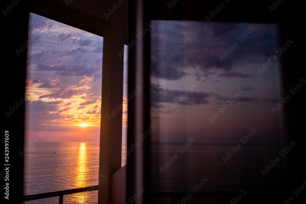 Fototapeta premium Beautiful sunset above the sea or the ocean, tropical resort. View from the hotel window