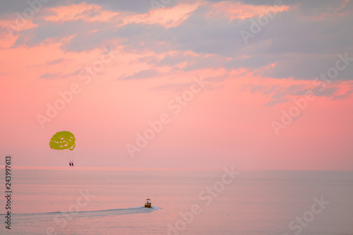 Yellow parasail wing pulled by a boat on beautiful pink sunset