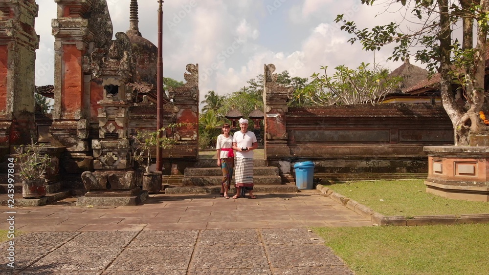 4K aerial flying drone video of european tourist in traditional clothes in the balinese temple.
