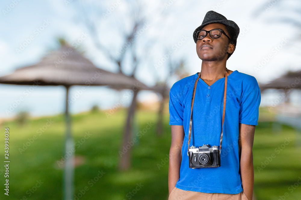 Naklejka premium Portrait of a smiling afro american man making photo on retro camera