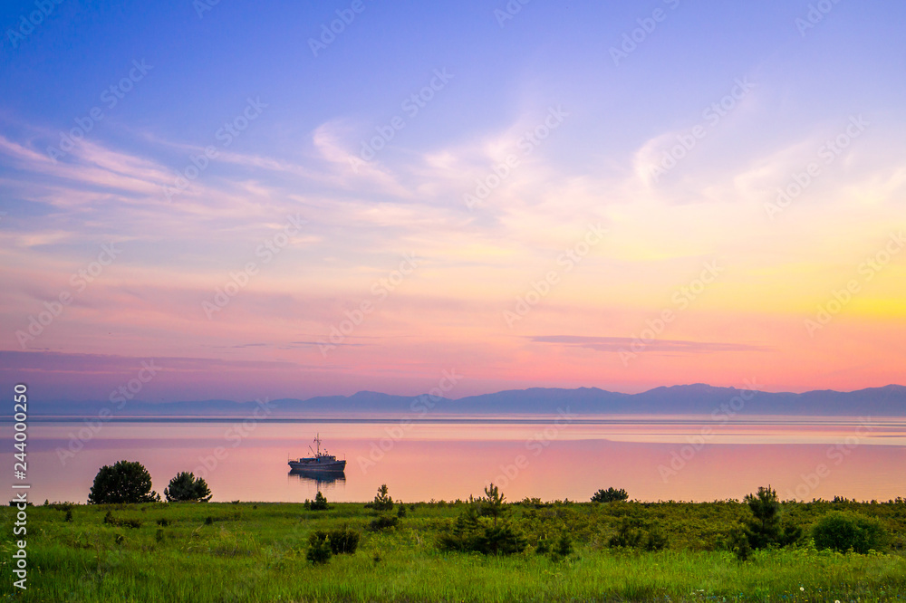 Baikal lake sunset in Barguzin nature reserve with a boat and mountains Baikal lake sunset in Barguzin nature reserve with a boat and mountains