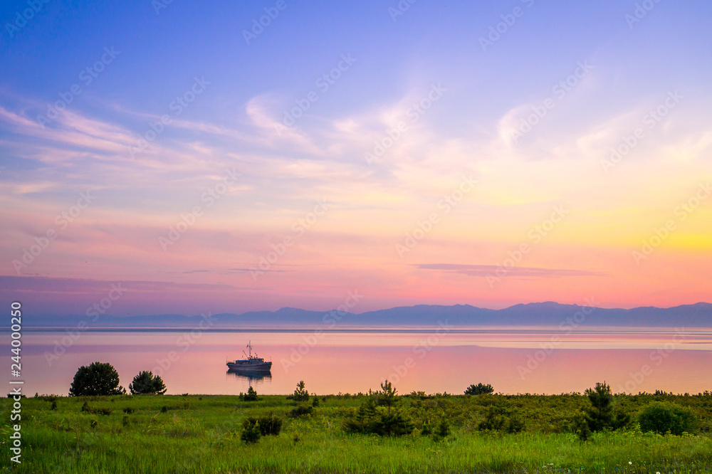 Baikal lake sunset in Barguzin nature reserve with a boat and mountains