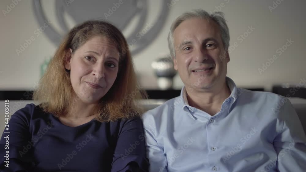 Couple of middle aged parents talking to adult children. Front view of man and woman waving hands, saying Hello, nodding and speaking at camera. Video chat concept Couple of middle aged parents talking to adult children. Front view of man and woman waving hands, saying Hello, nodding and speaking at camera. Video chat concept