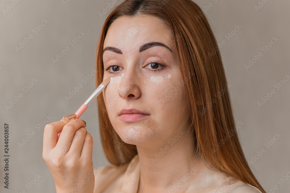 Woman with problem skin prone to rashes and acne, acne scars put on make up concealer and foundation , concept of healthy skin, dermatology and cosmetology Woman with problem skin prone to rashes and acne, acne scars put on make up concealer and foundation , concept of healthy skin, dermatology and cosmetology
